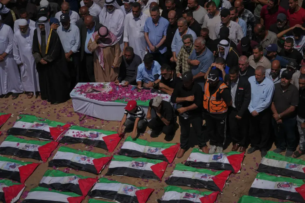 Mourners gather around the flag-draped bodies of members of the...