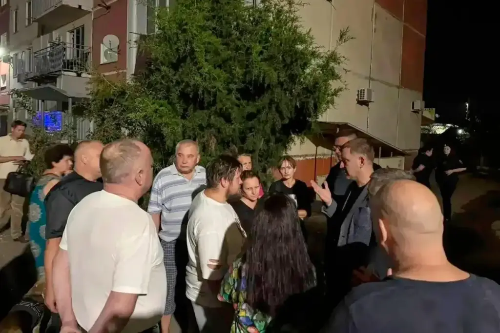 Local citizens listen to a representative standing near an apartment after a Ukrainian drone attack.