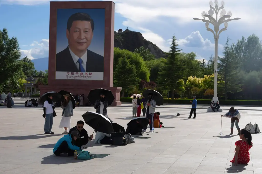 Tourists rest near a portrait of Chinese President Xi Jinping at a public square.