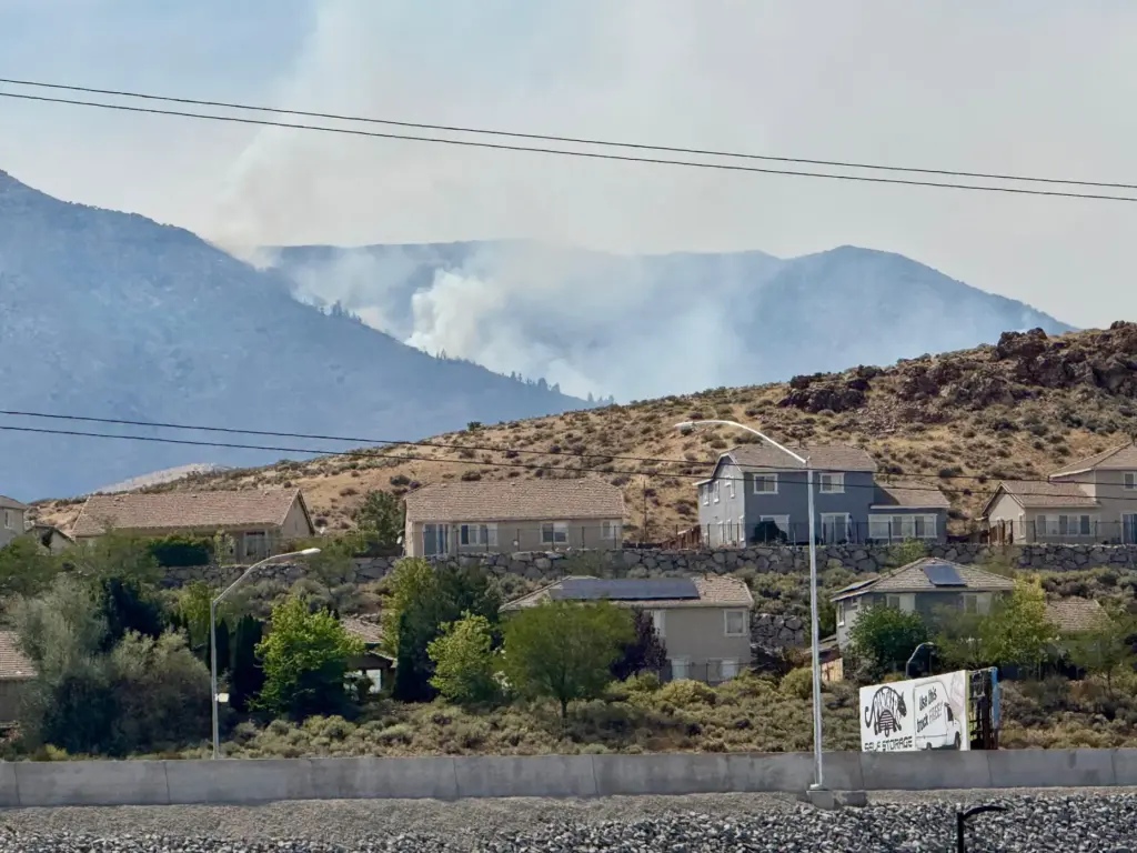 Smoke billows in the distance as a wildfire burns in...