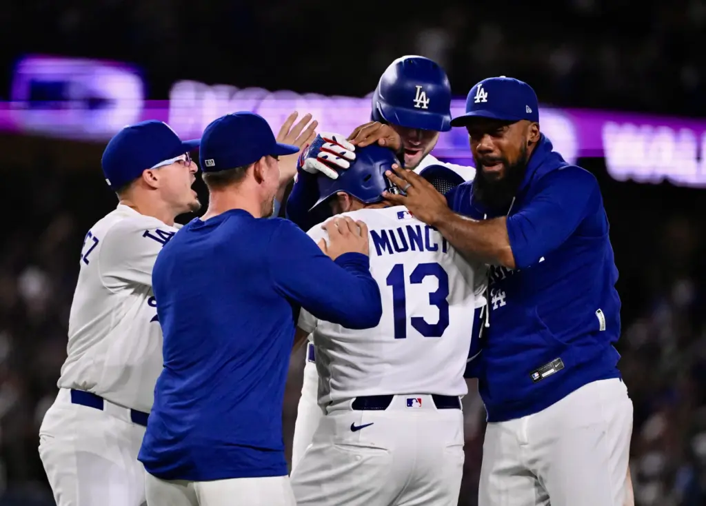 The Dodgers’ Max Muncy (13) is mobbed by teammates after...