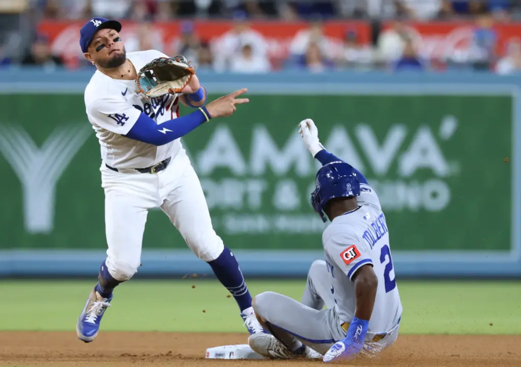 Dodgers second baseman Miguel Rojas throws to first to complete...