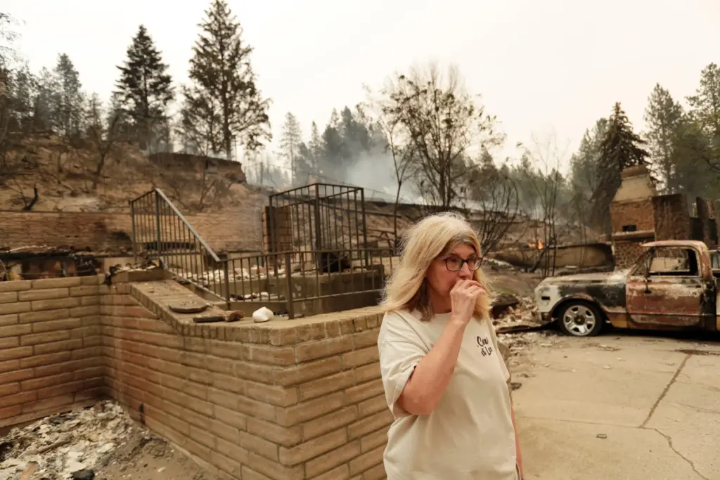 Kimberley Sather stands at the duplex she rents after it burned in a wildfire.