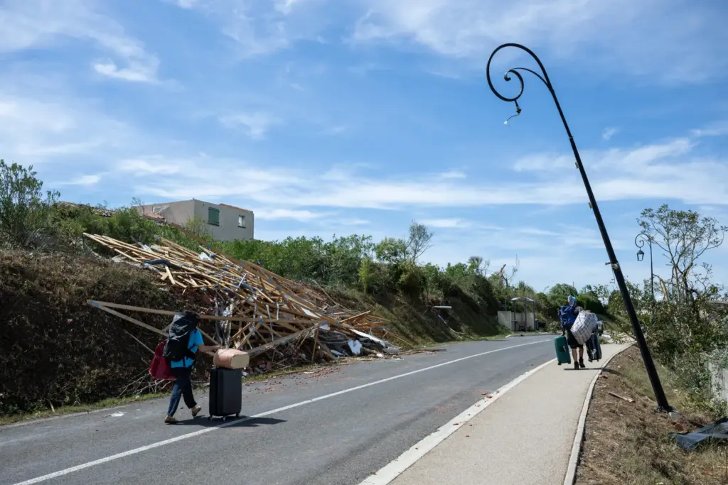 People leave with luggage after a tornado ravaged the small...