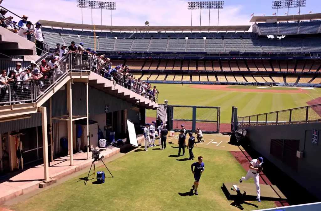 Shohei Ohtani, right, of the Dodgers leaps over the practice...