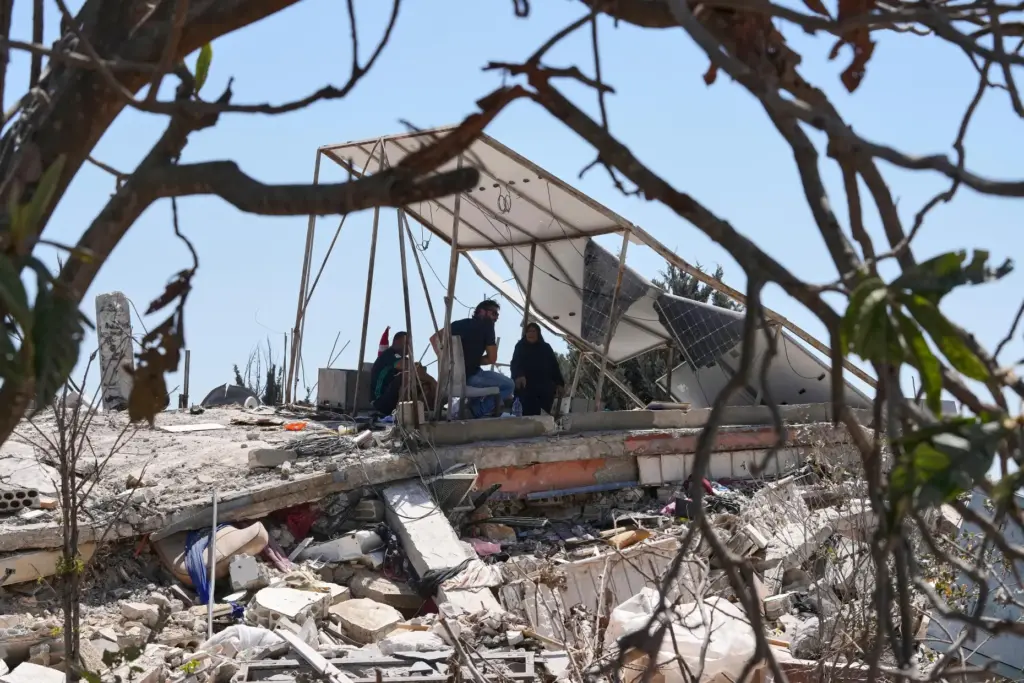 A Lebanese family takes shade under the damaged solar panels of their destroyed house.