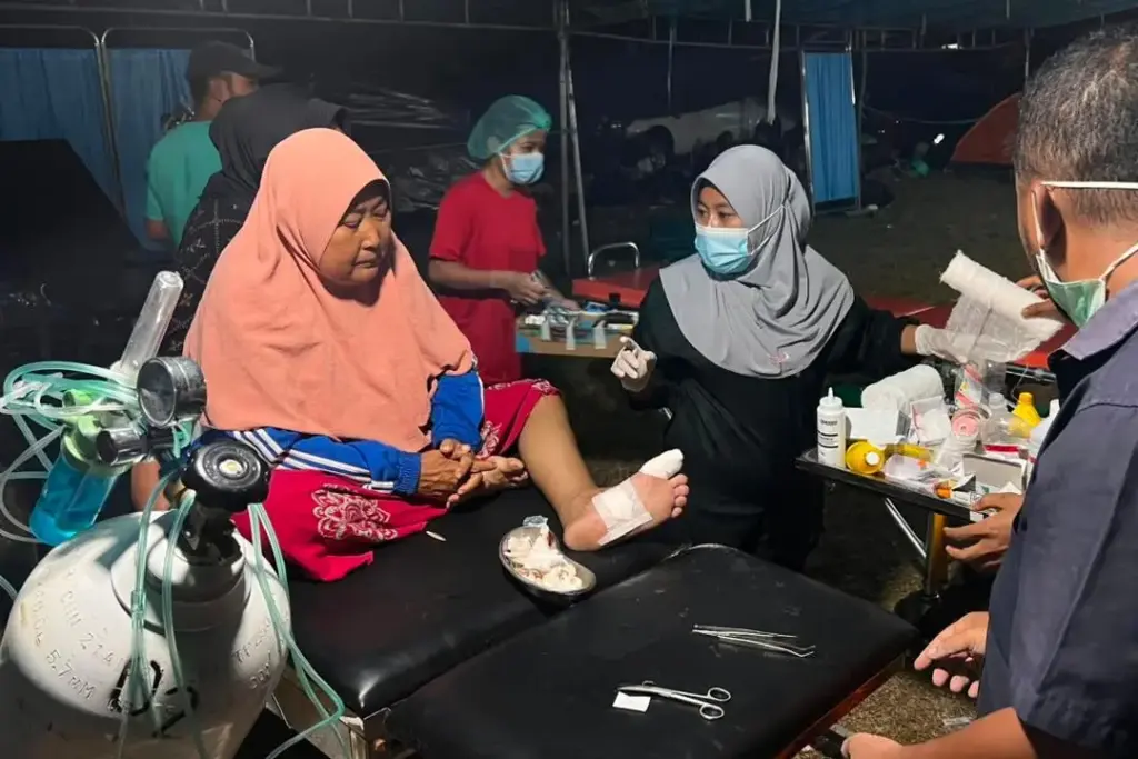 An earthquake survivor receives medical treatment at a makeshift medical center in Reo, Indonesia.