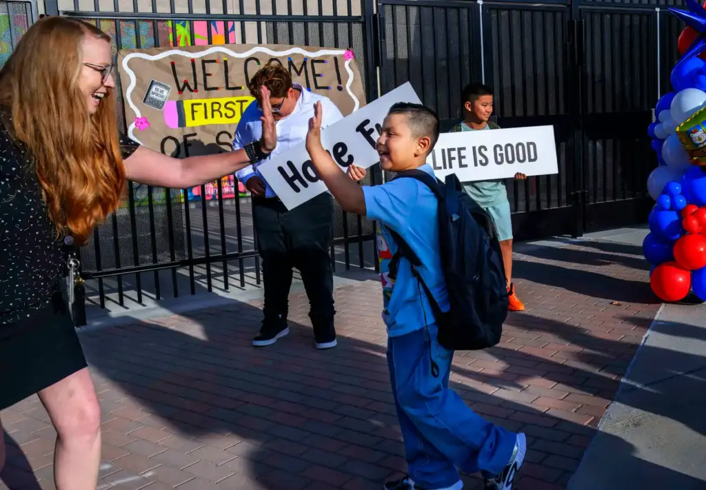 Music teacher Christina Flynn, left, welcomes a student on the...