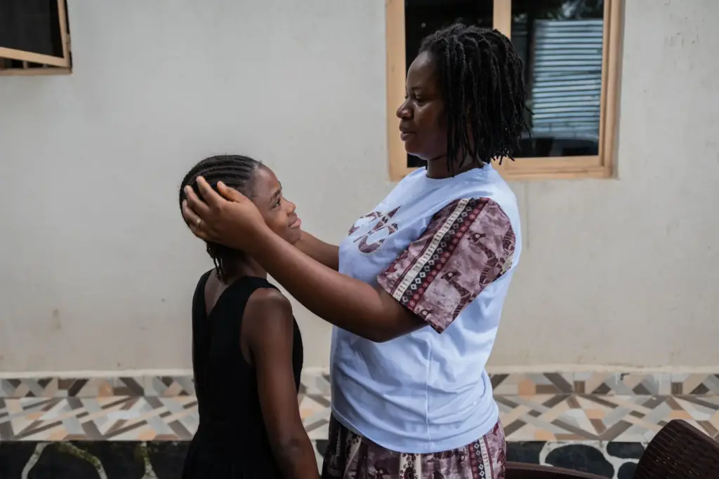 Esther Lutula caresses her child outside her house.