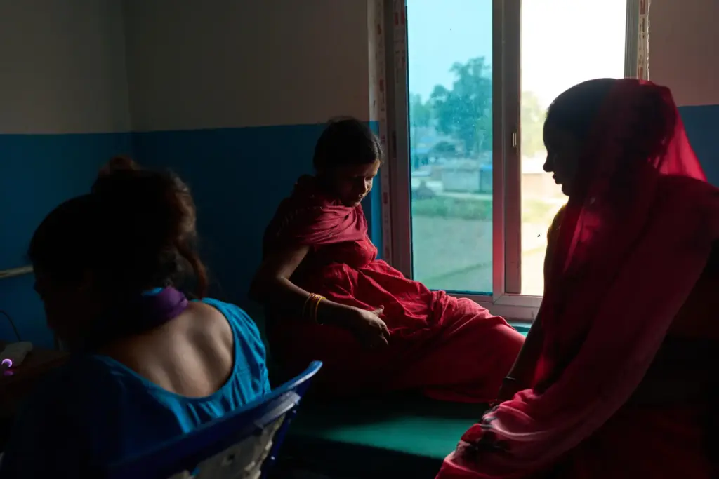 Nitu Devi, 22, who is pregnant, sits on a bed before an ultrasound.