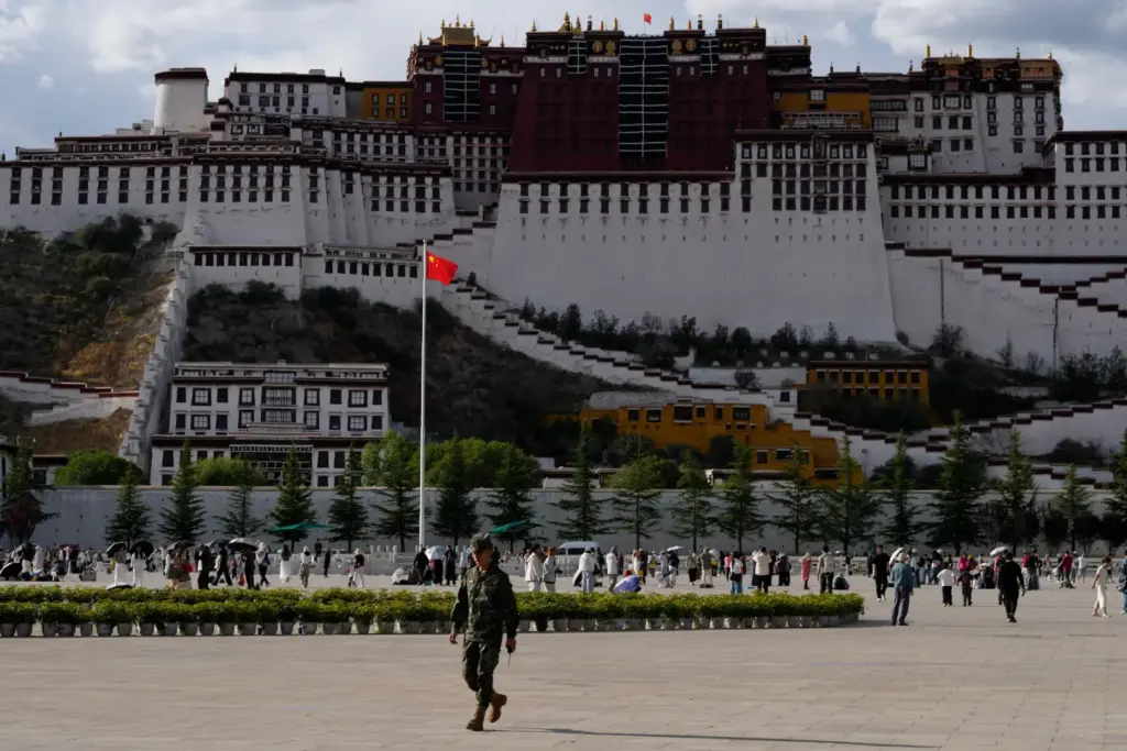 A soldier walks on a public square where a Chinese national flag hangs.