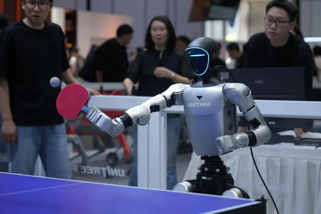 Exhibitors watch a robot play table tennis.