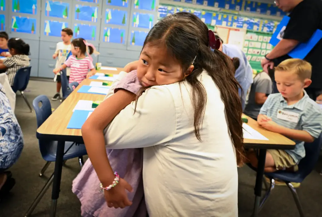 Rumi Song holds on to her mom, Sarah Choi, before...