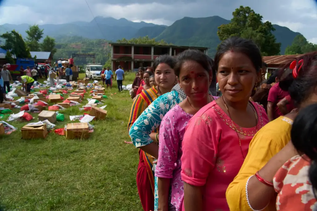 Survivors stand in a queue to receive relief supplies in...