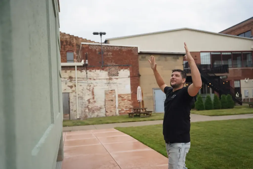 Wesley Mast gestures next to a giant replica of a Hoosier cabinet.