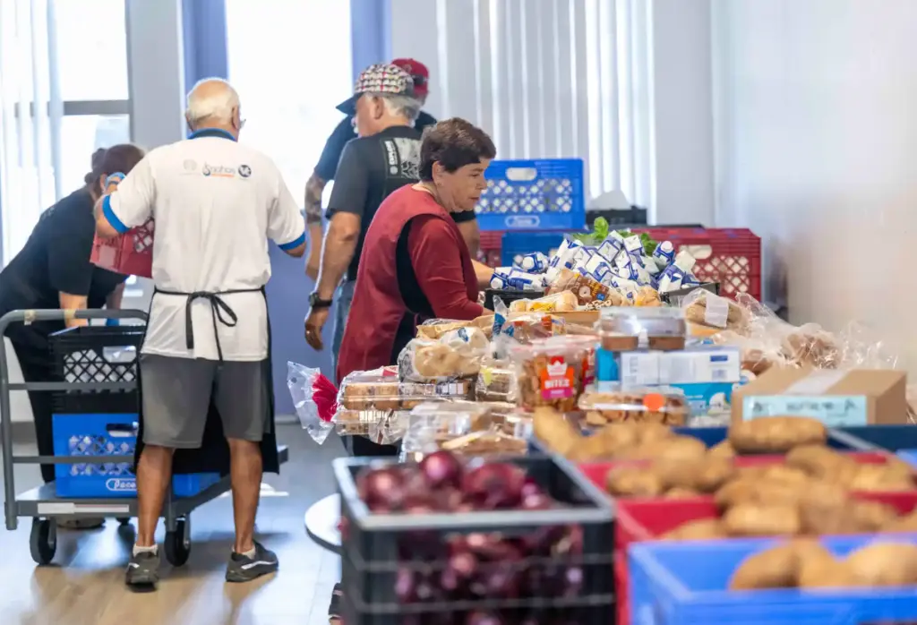 Volunteers help organize tables of food to be given out...