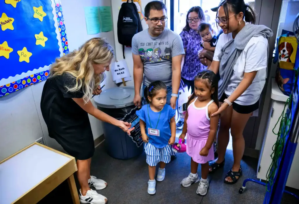 TK teacher Tiffany Rath, left, greets students, including Rose Romero,...