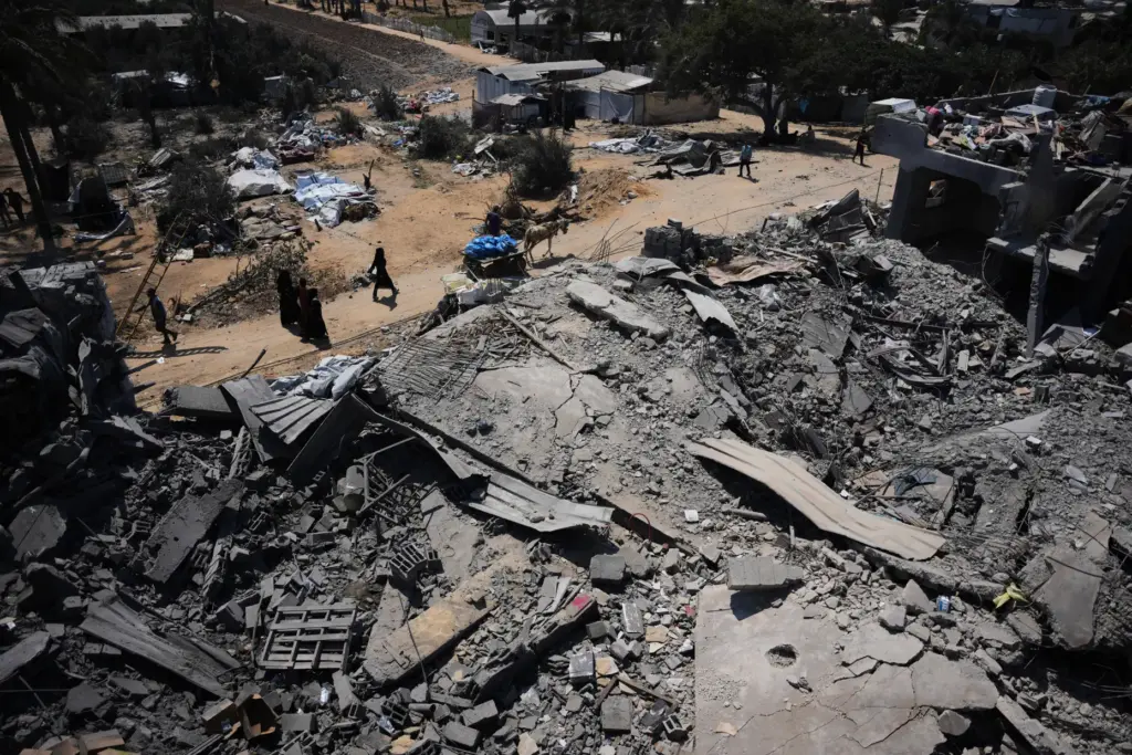 Palestinians walk past a food-aid warehouse damaged in an Israeli airstrike.