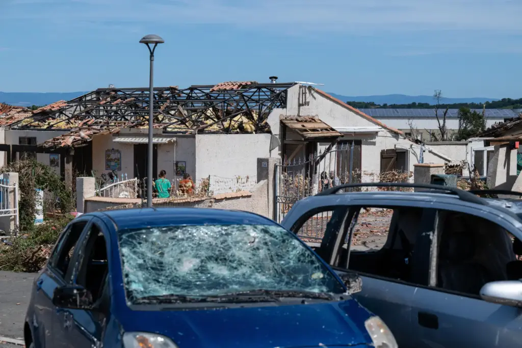 Cars and a damaged house are pictured after a tornado...