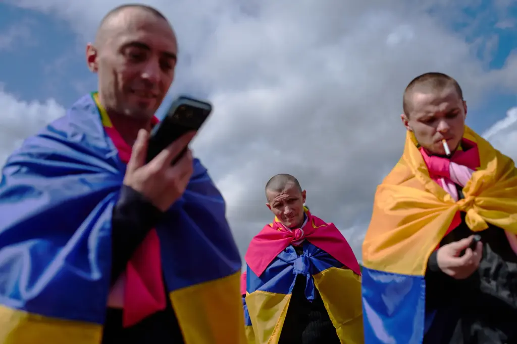 Ukrainian soldiers smoke and talk to their relatives after returning from captivity.