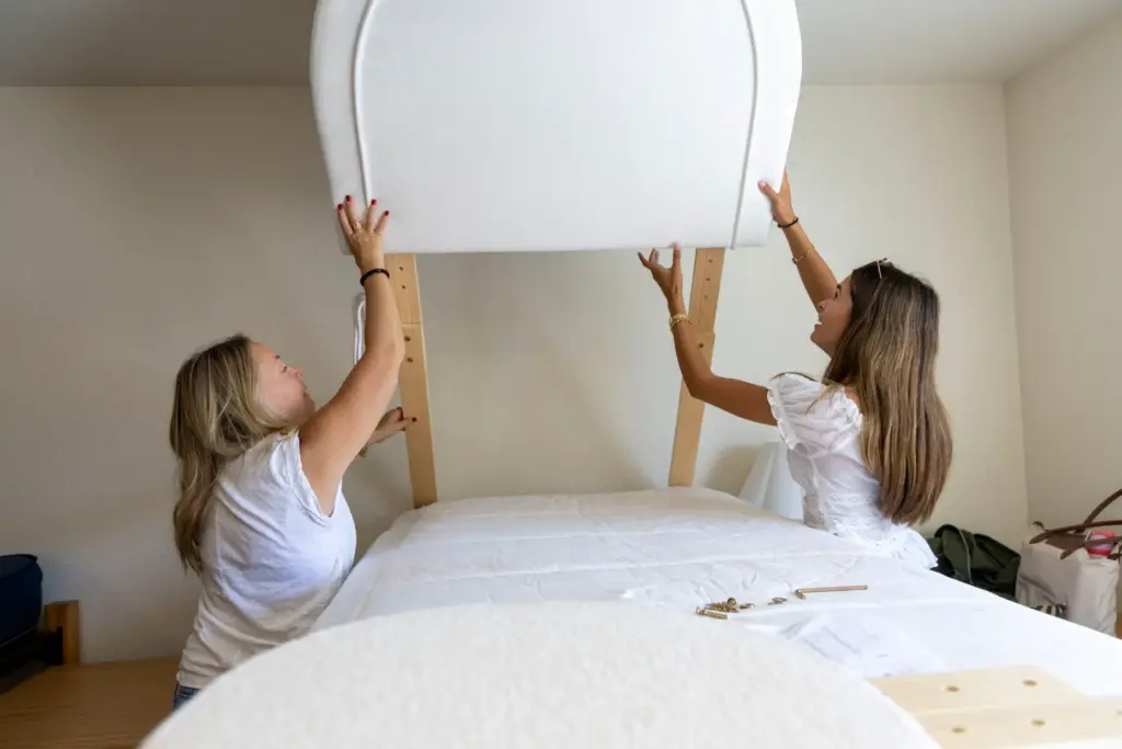Jill Ostren, on the left, lifts a headboard with her...