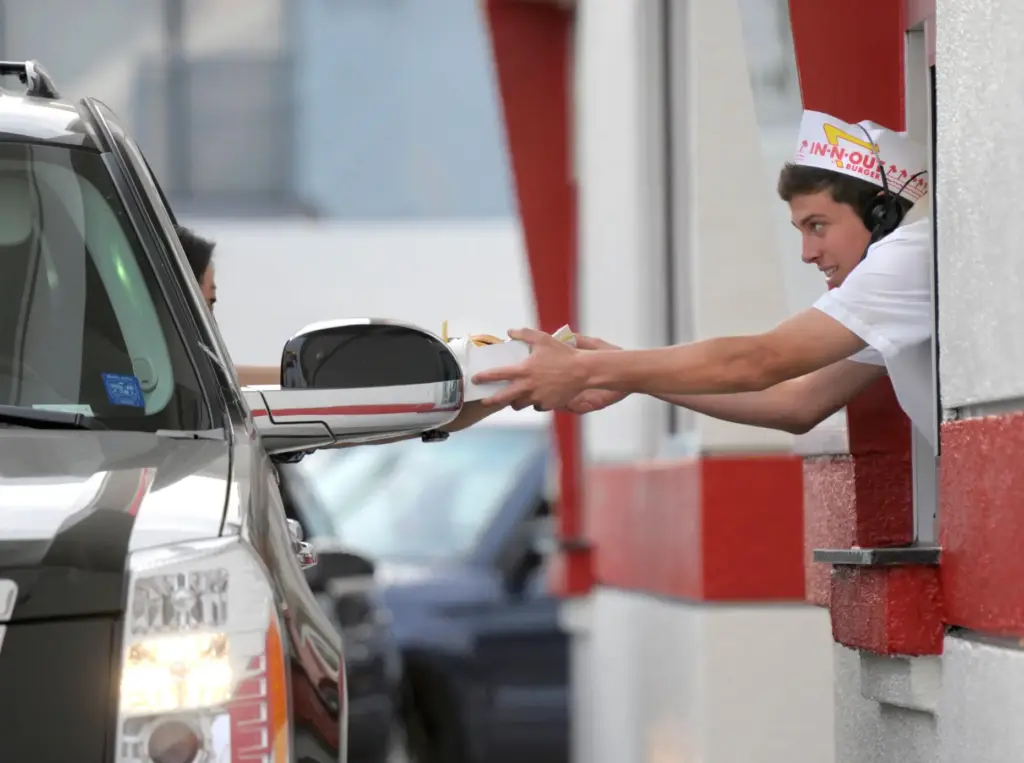 A customer receives her burger and fries from the drive-thru at In-N-Out Burger.