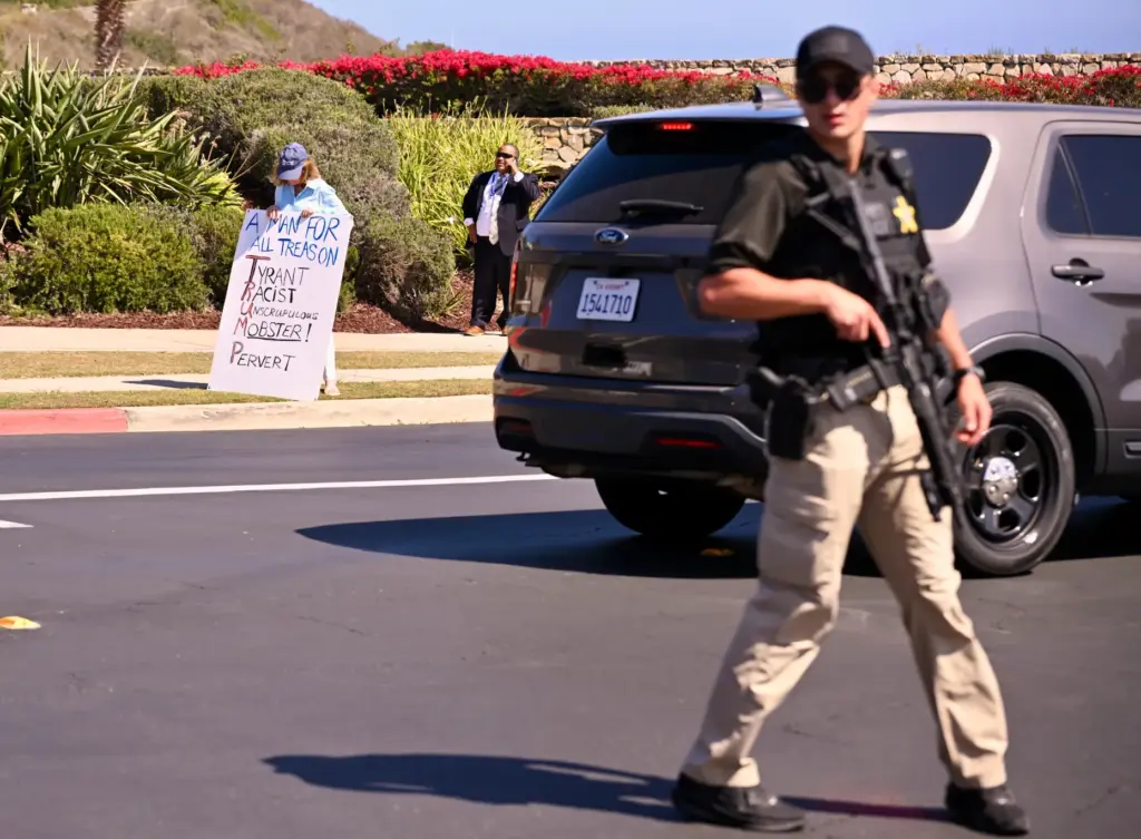 A protester stands in front as a secret service agent...