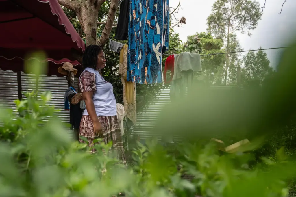 Esther Lutula stands outside her house.