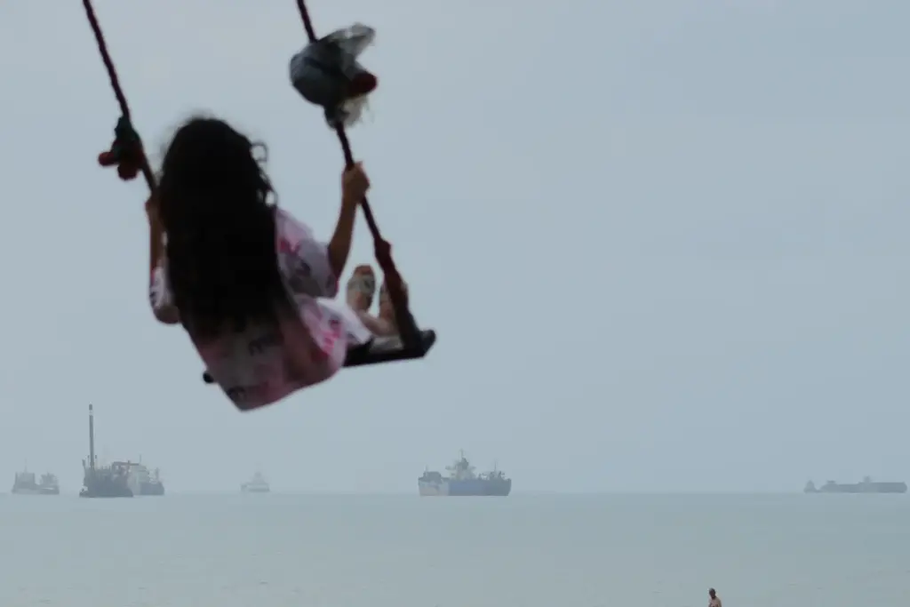 A girl swings along the shore of the Strait of Hormuz.