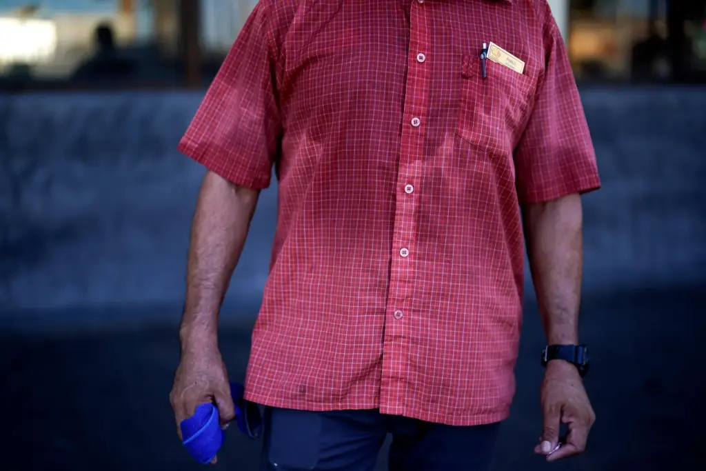 FILE – A man’s shirt is bathed in sweat before...
