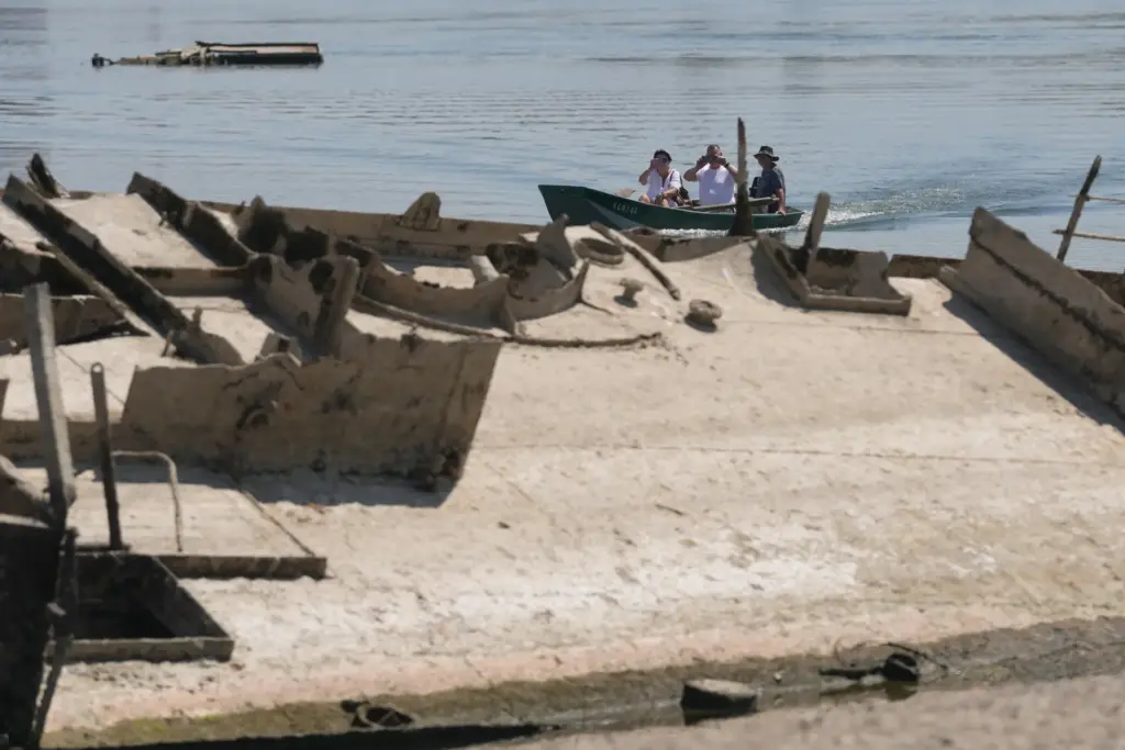 People watch the wreckage of a WWII German warship, emerged...