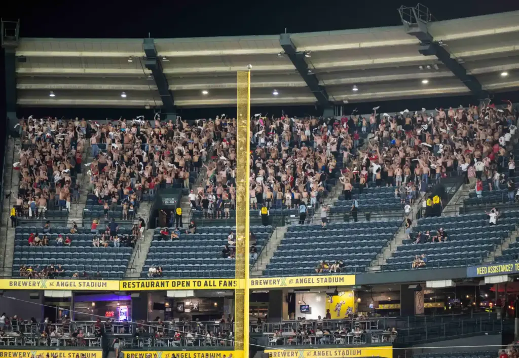 A group of young male fans wave their shirts in...
