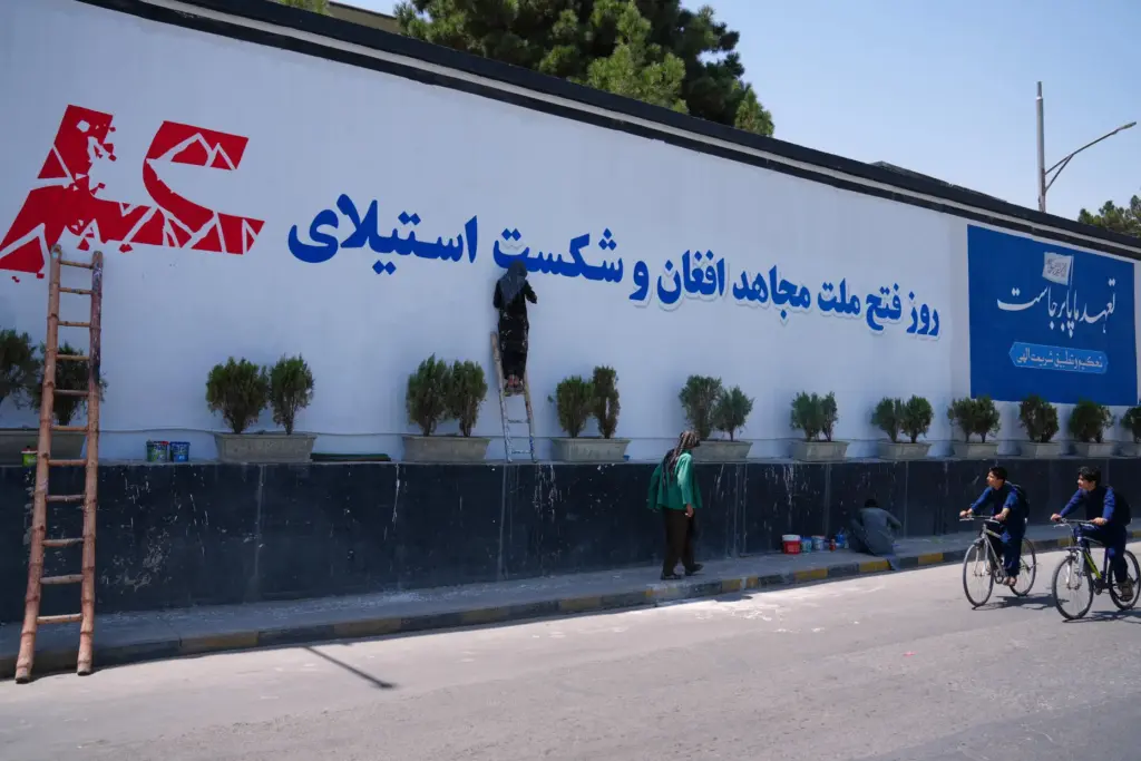 Workers paint a mural celebrating the Taliban’s victory and the...