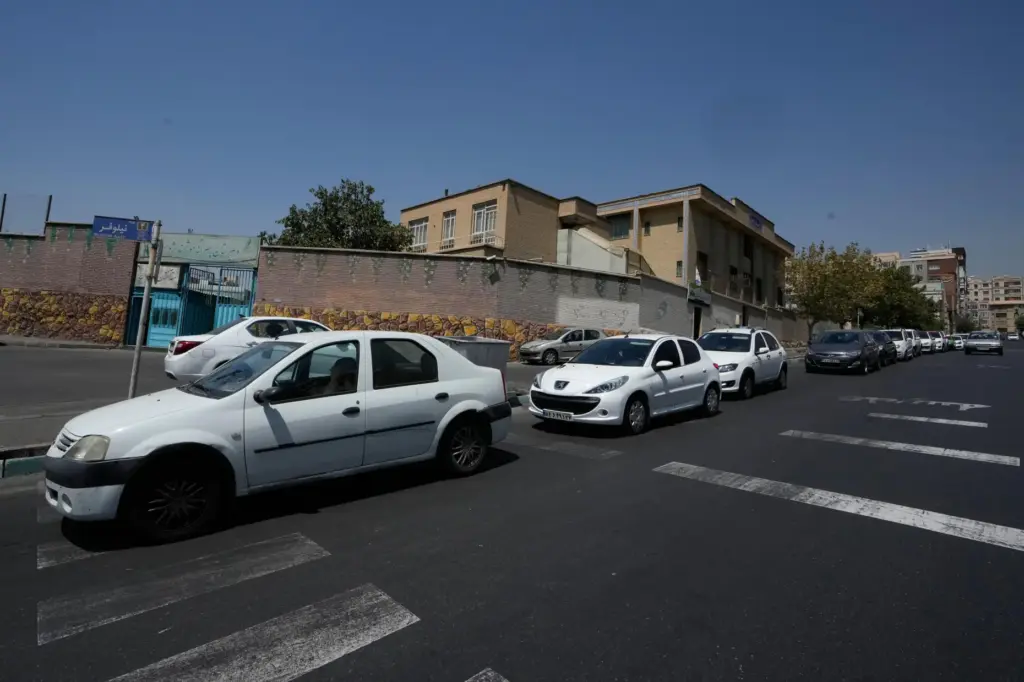 Cars line up outside a gas station in Tehran, Iran,...
