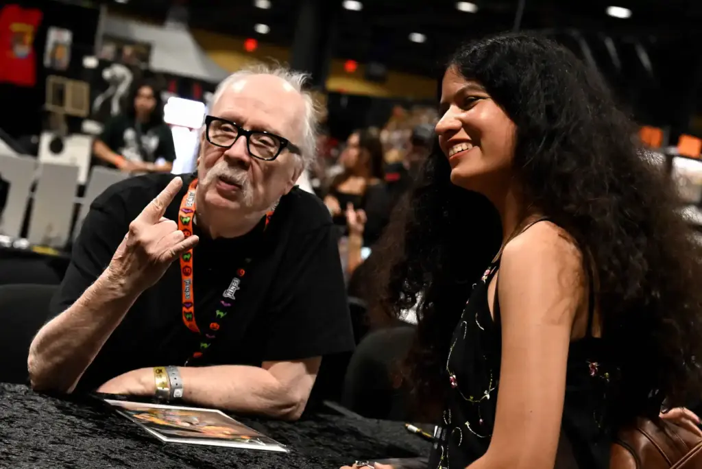 Director John Carpenter poses for photos with a fan during...