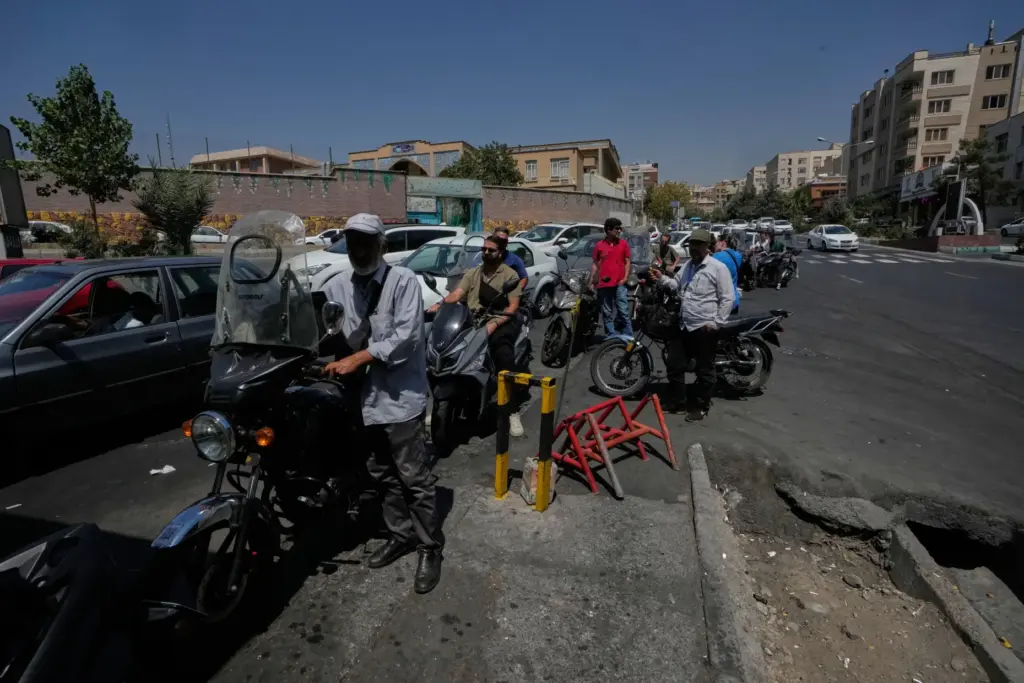 Motorcycles and cars line up outside a gas station in...