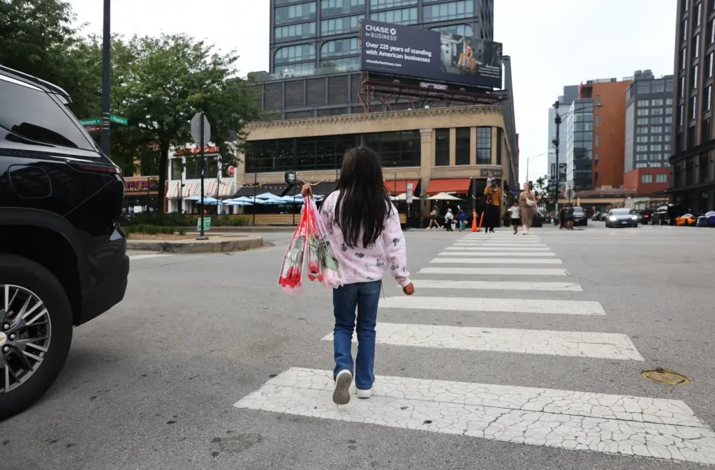 A child crosses at Randolph and Peoria streets while selling flowers.
