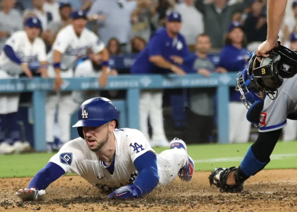 The Dodgers’ Kyle Tucker slides home to score on a...