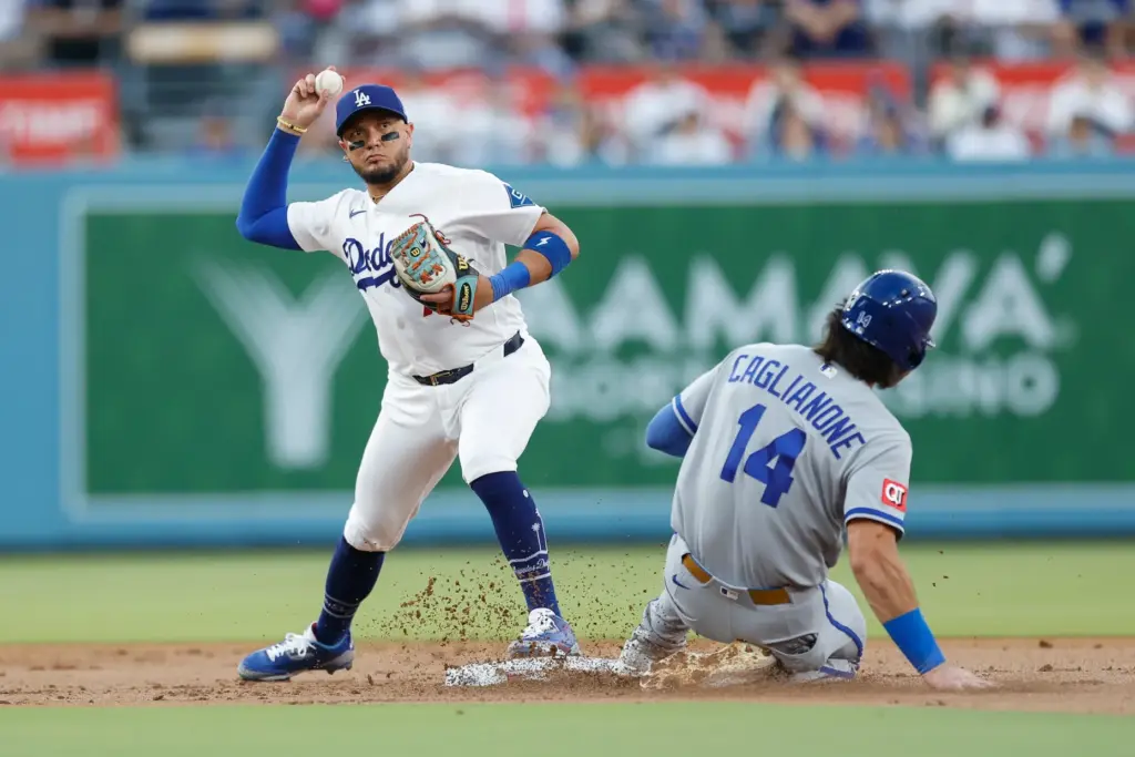 Dodgers second baseman Miguel Rojas, left, throws to first base...