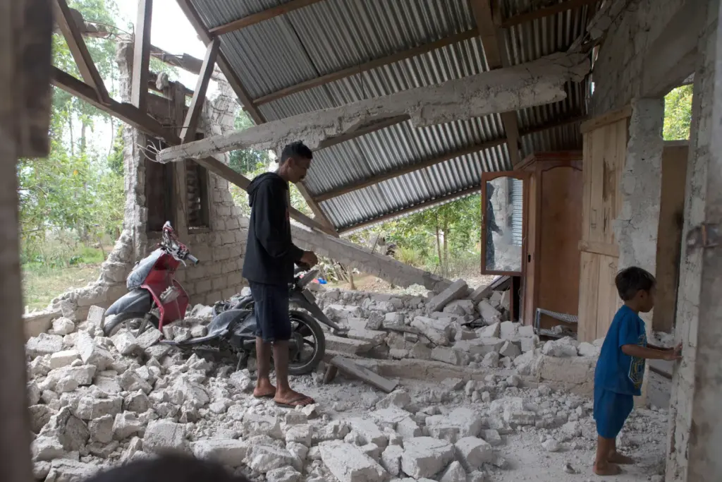 Saverinus Serli inspects his earthquake-damaged house in Lelak, Indonesia.