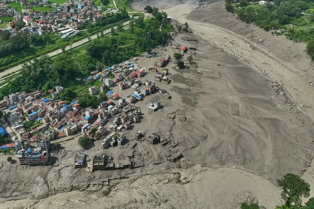 Damaged houses stand precariously near the swollen banks of the Trishuli River.