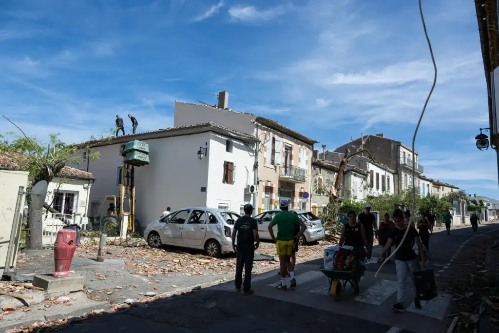 Resident watch damaged houses after a tornado ravaged the small...