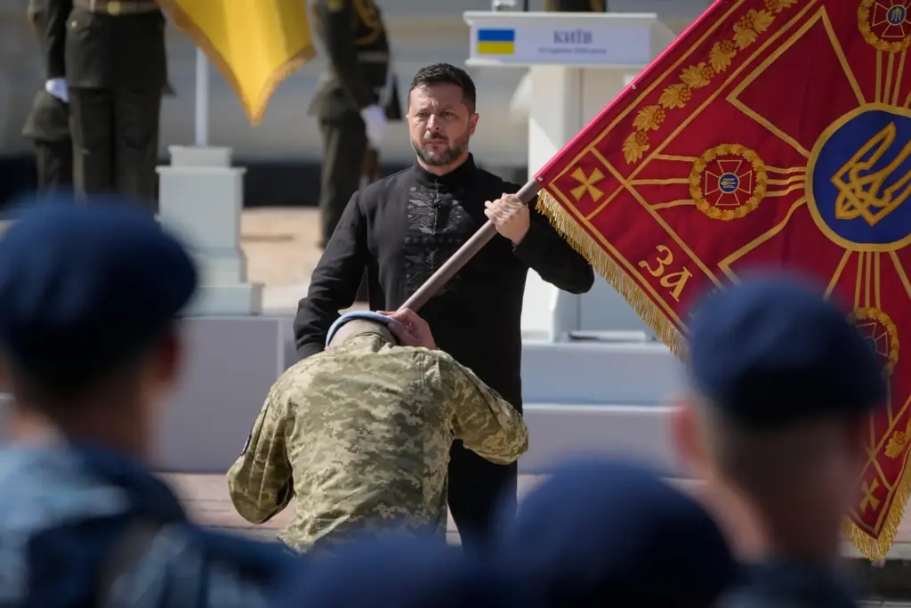 Ukraine's President Volodymyr Zelenskyy hands over the flag of a military unit.