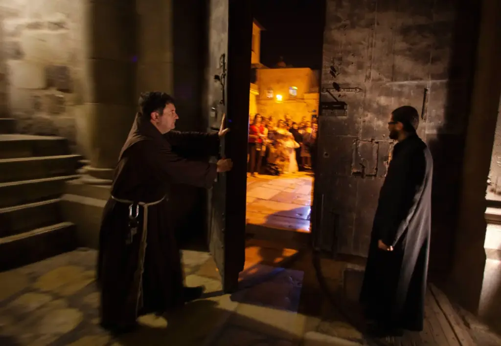 A priest closes the door to the Holy Sepulcher church for the night.