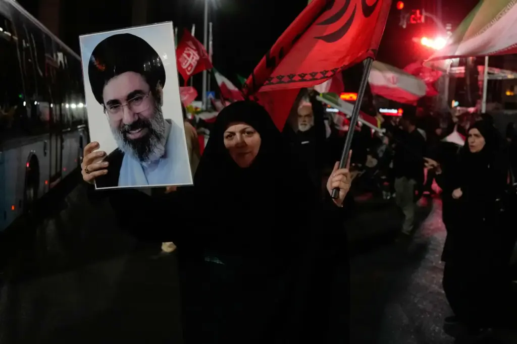 A woman holds up a poster of Iranian Supreme Leader Ayatollah Mojtaba Khamenei.