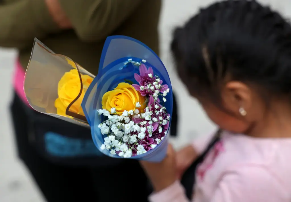 A mother named MarÃ­a stands with her 6-year-old child on a street corner.