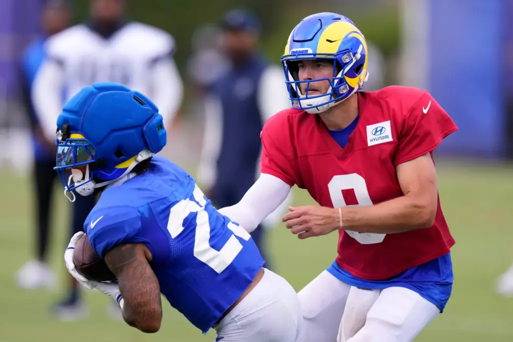 Rams quarterback Matthew Stafford, right, hands the ball off to...