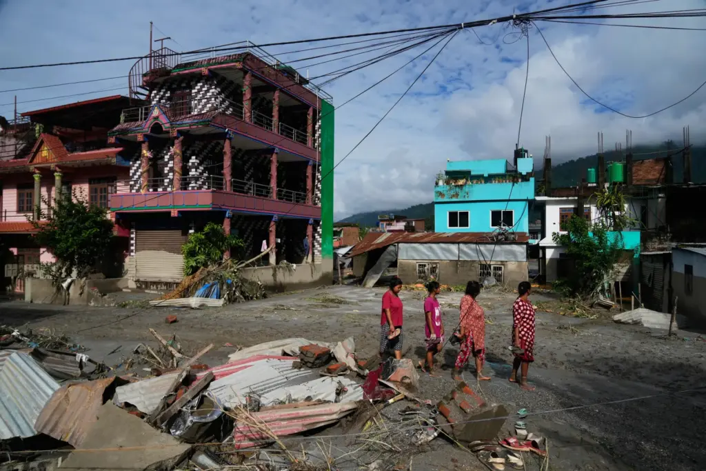 People walk past damage in the aftermath of flash floods...