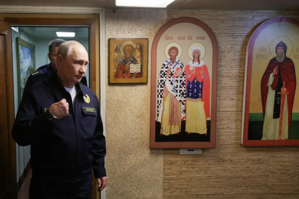 Russian President Vladimir Putin crosses himself as he visits the Varyag missile cruiser.
