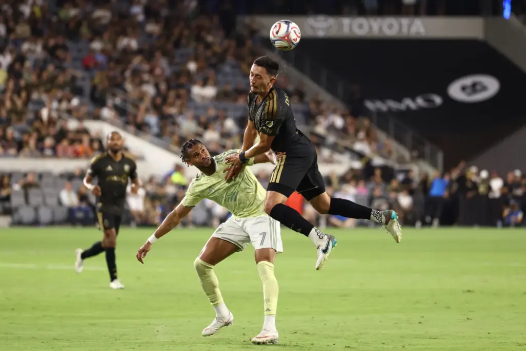 LAFC midfielder Mark Delgado, top, heads the ball against Portland...